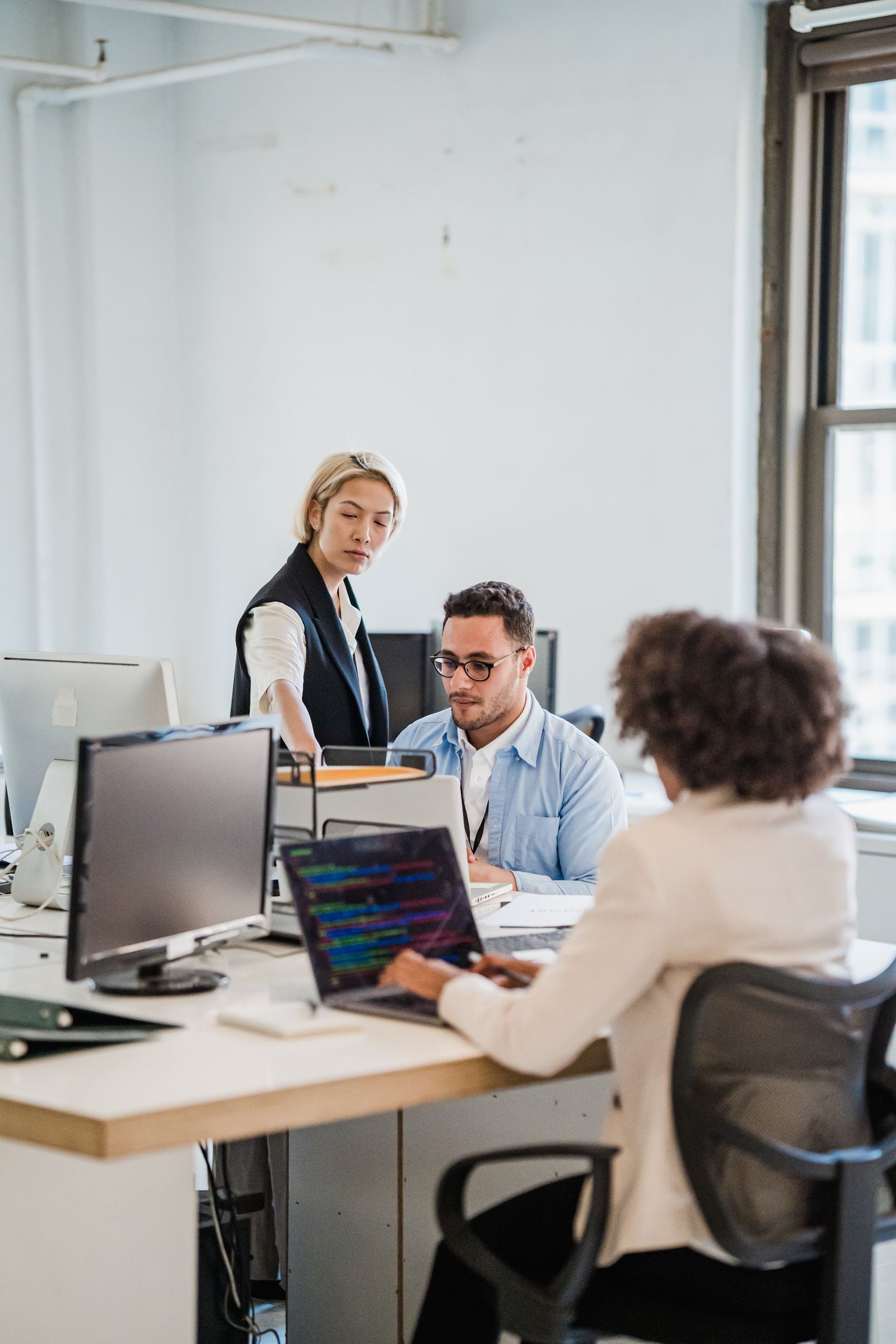 IT professionals collaborating around laptops in a modern workplace